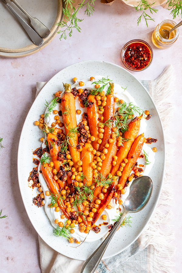 Een heerlijke groenteschotel van geroosterde peen met krokante kikkererwten en crispy chili-olie. Met balsamicoazijn en honing, smullen!