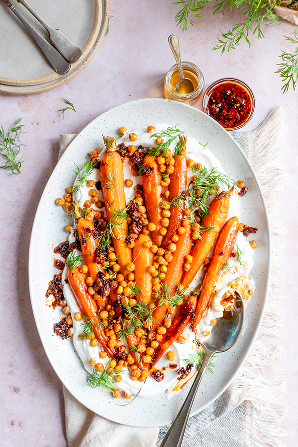 Een heerlijke groenteschotel van geroosterde peen met krokante kikkererwten en crispy chili-olie. Met balsamicoazijn en honing, smullen!