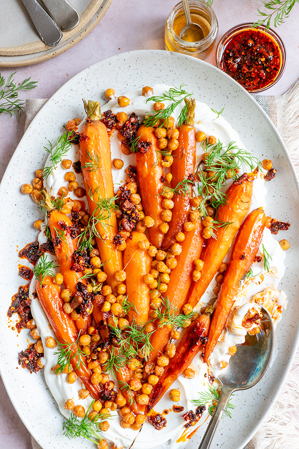 Een heerlijke groenteschotel van geroosterde peen met krokante kikkererwten en crispy chili-olie. Met balsamicoazijn en honing, smullen!