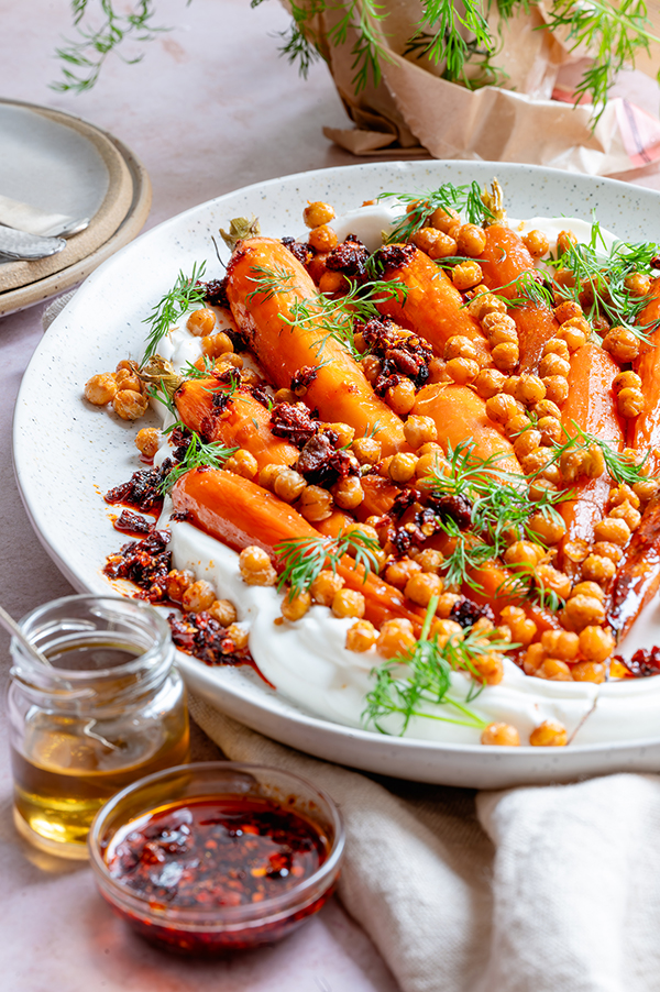 Een heerlijke groenteschotel van geroosterde peen met krokante kikkererwten en crispy chili-olie. Met balsamicoazijn en honing, smullen!